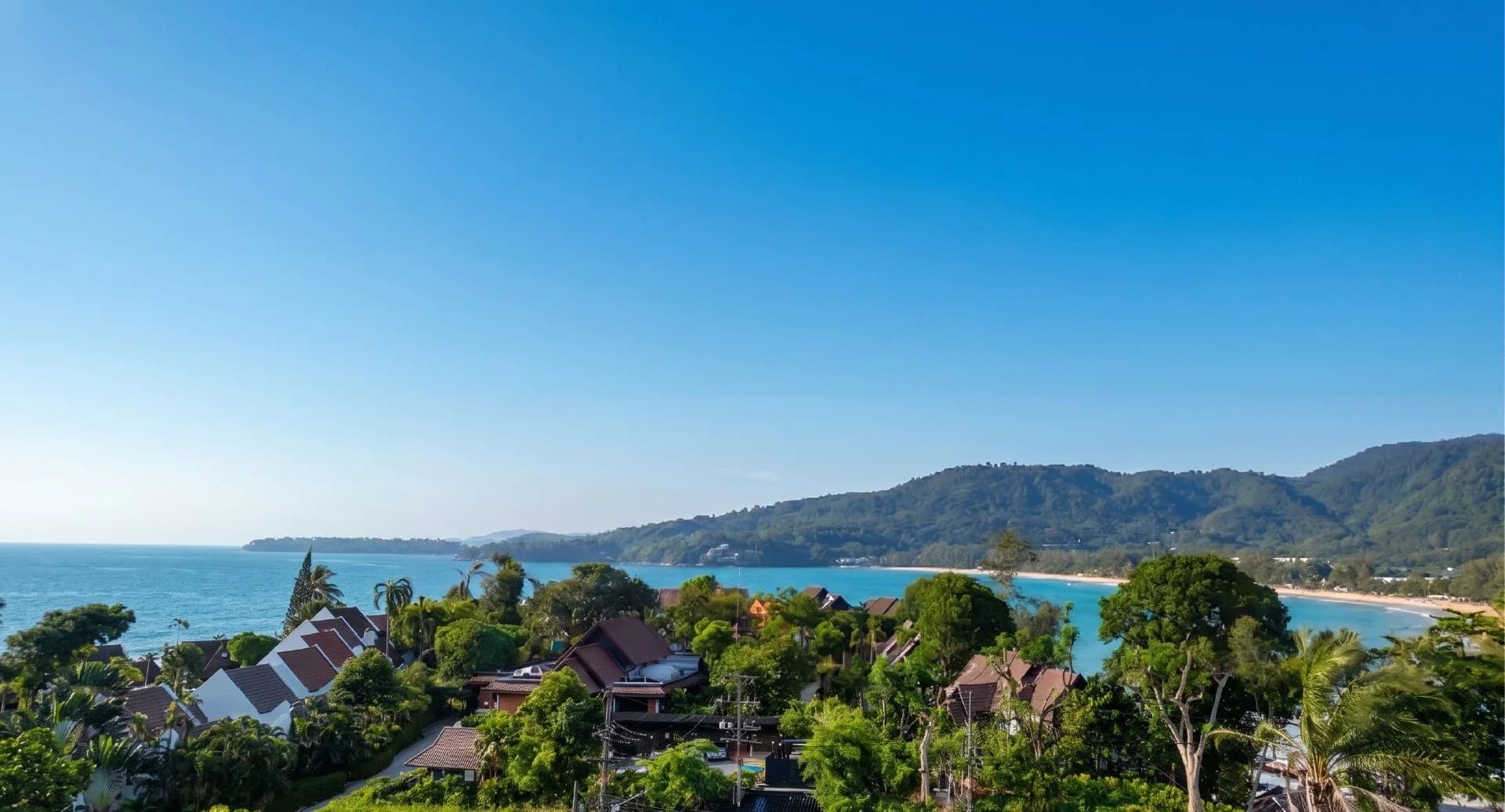From plot B1: an open view over Thai roofs to Kamala Bay and the green headland